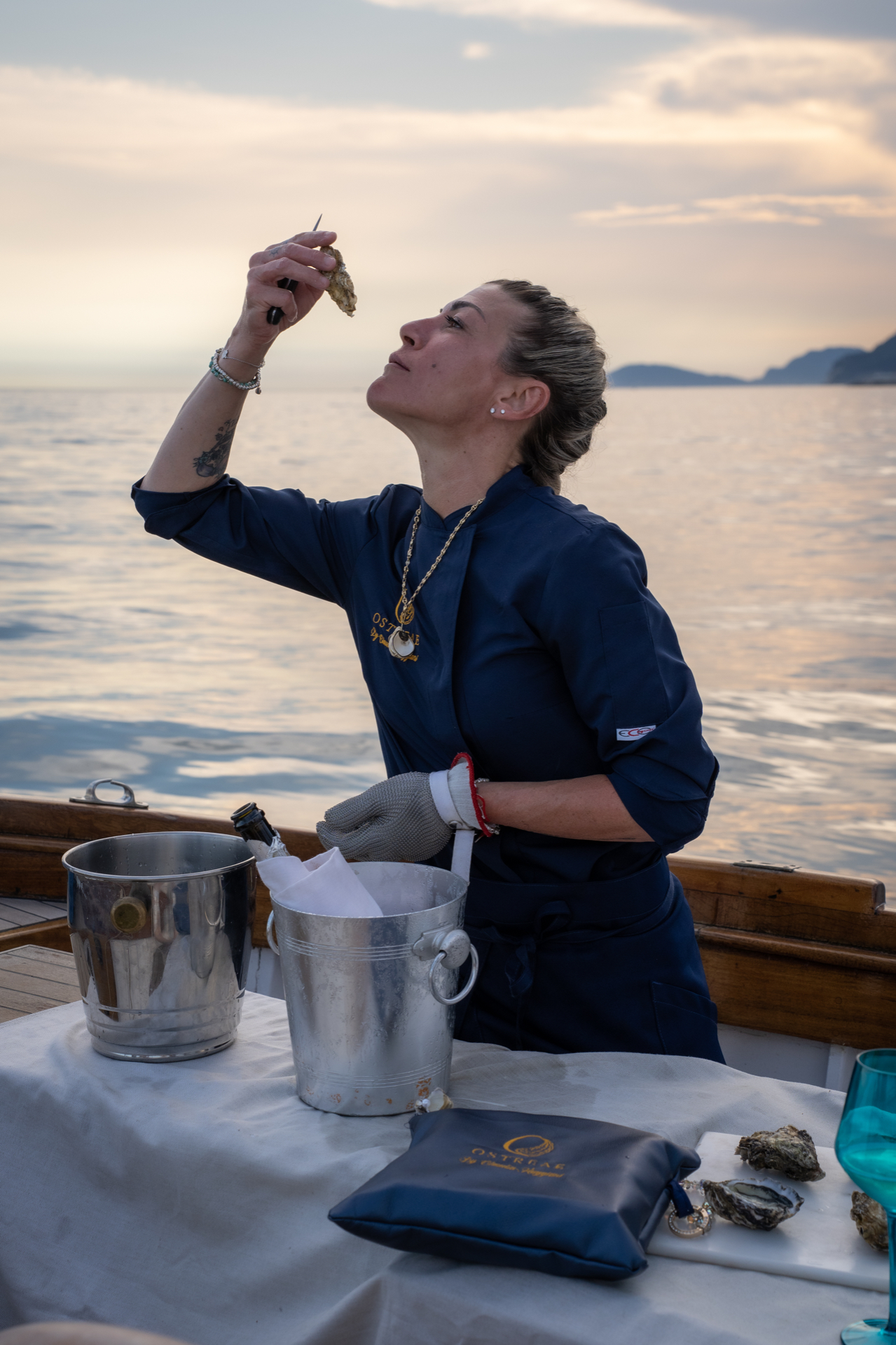 Claudia Maggiani apre un'ostrica in barca al tramonto